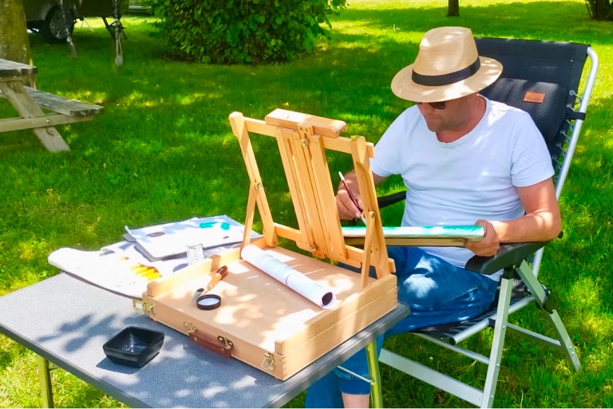 Gideon schildert buiten aan een persoonlijk kunstwerk en doet inspiratie op in de natuur.