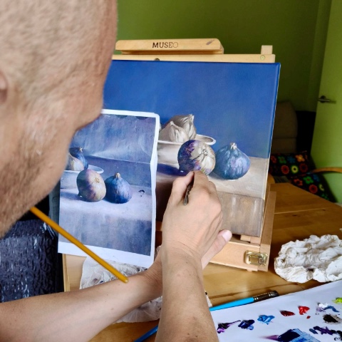 Gideon schildert met de hand een persoonlijk schilderij op basis van een foto.