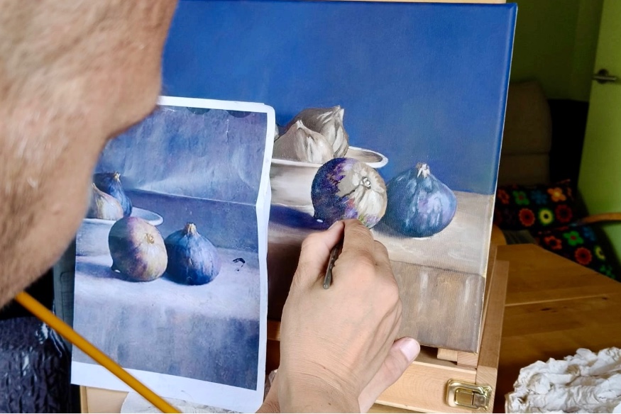 Gideon schildert een origineel stilleven op doek aan de hand van een referentiefoto.