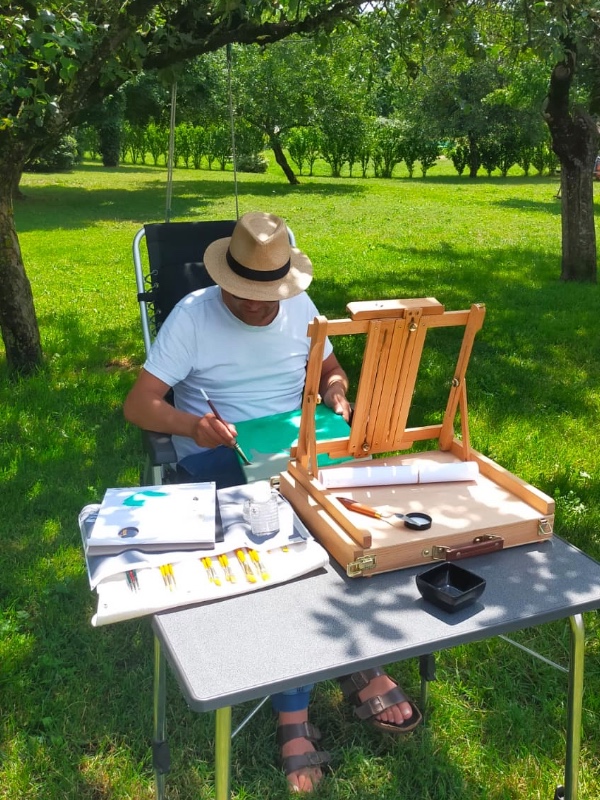 Gideon, schilder van Gigi's Schilderatelier schildert buiten een persoonlijk olieverfschilderij met olieverf op doek.